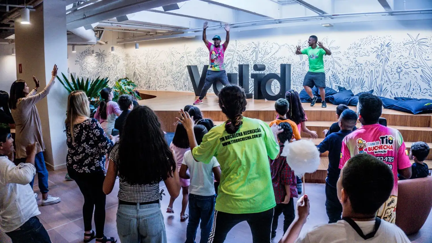 Tio Buchecha e um recreador dançam no palco enquanto as crianças acompanham a coreografia